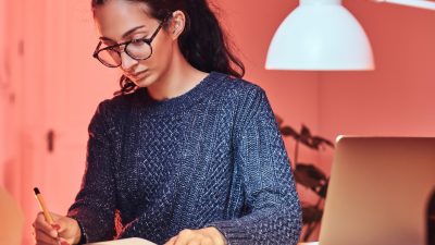 Young student is learning new material while sitting next to the table.